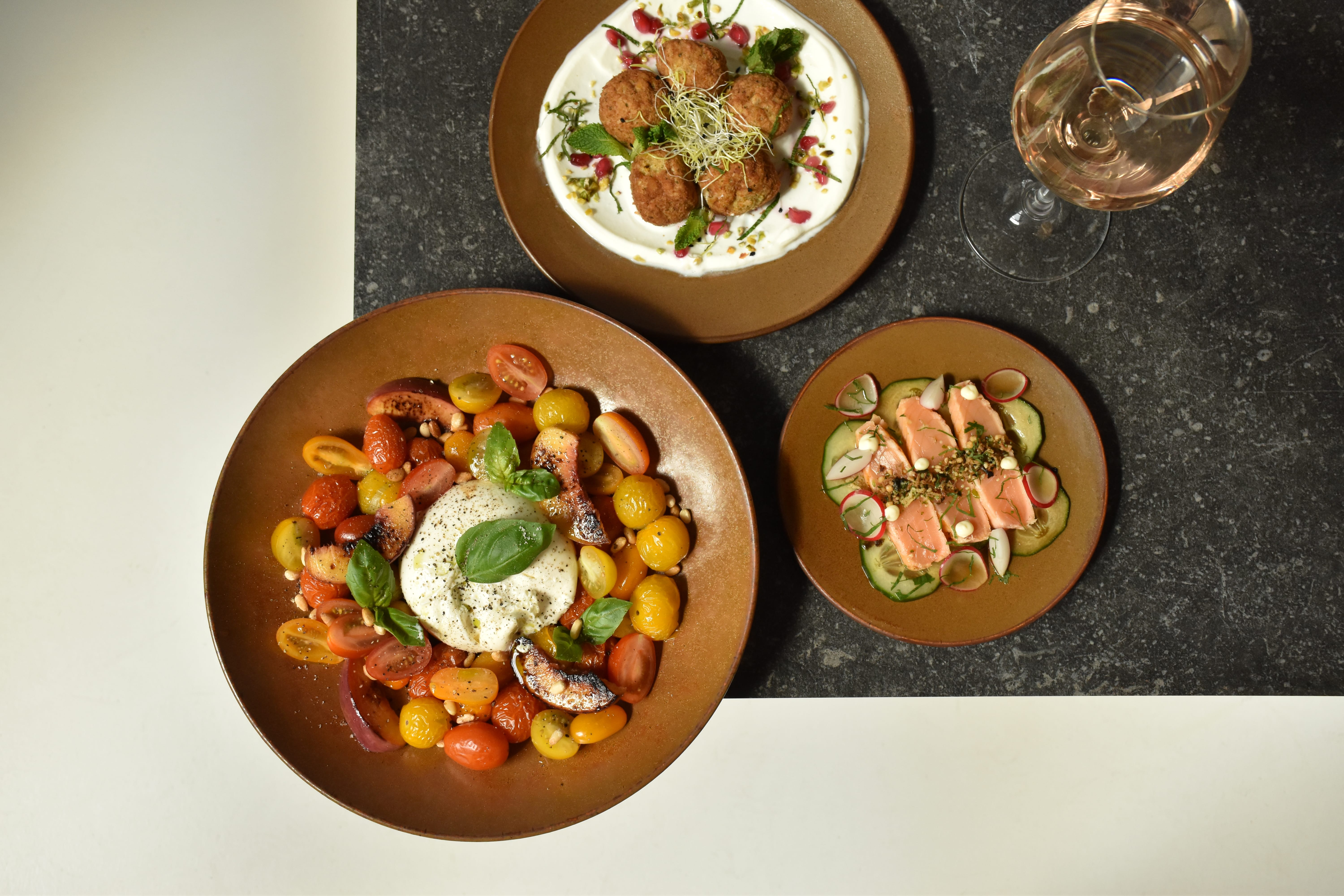De Ovio-borden presenteren drie verfijnde gerechten: zalm tataki, falafel met yoghurtdip en burrata met tomaat, in een perfecte balans van vorm en smaak.