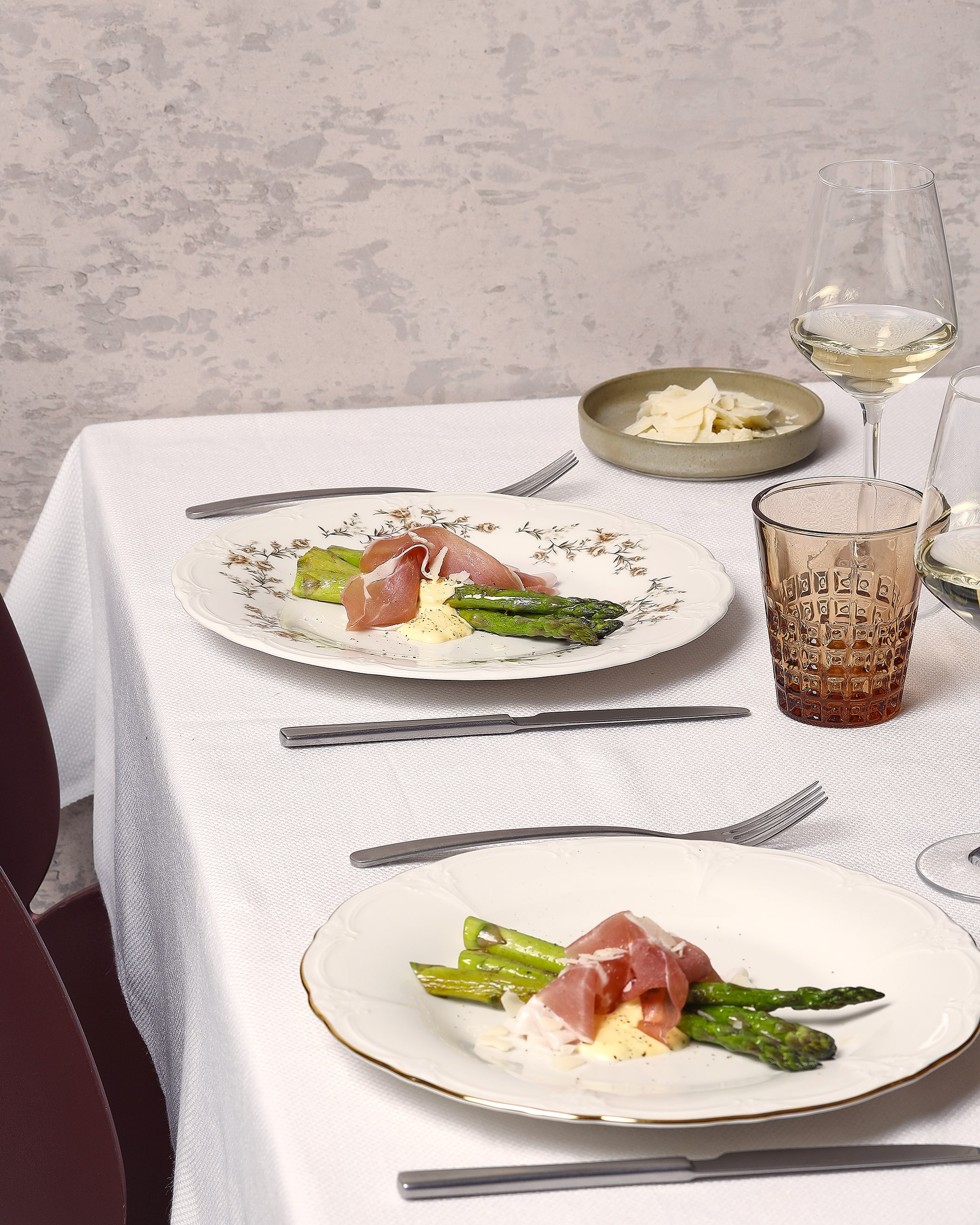 Retro collection of white plates in retro shape, covered with fresh asparagus.